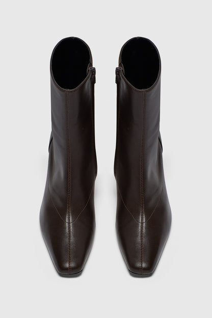 The Realm Encore Ankle Boots, crafted from black leather with square toes and visible stitching, are a chic addition to any capsule wardrobe, displayed from above on a light gray background.