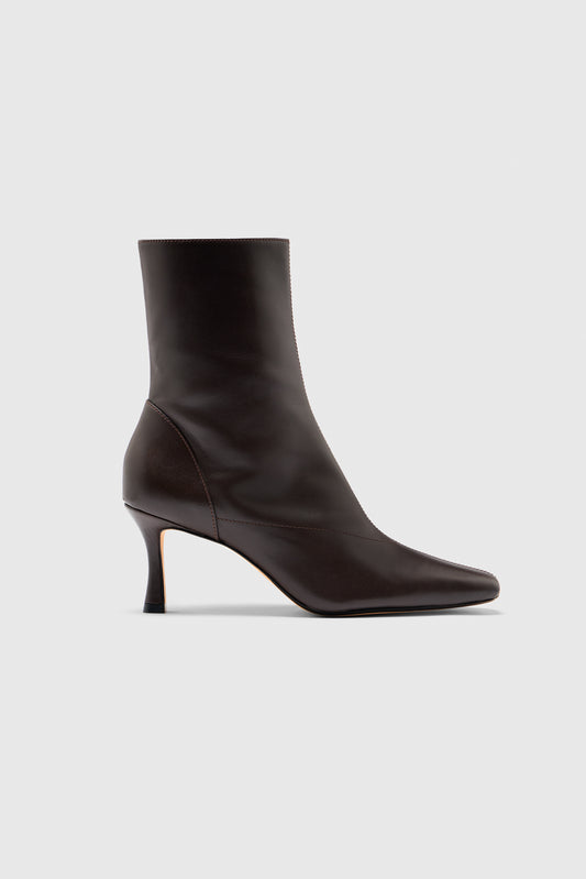 The Encore Ankle Boots by Realm—a sleek, black leather ankle boot featuring a pointed toe and a mid-height, slender heel—are shown in profile against a plain white background, offering an effortlessly elevated addition to any capsule wardrobe.