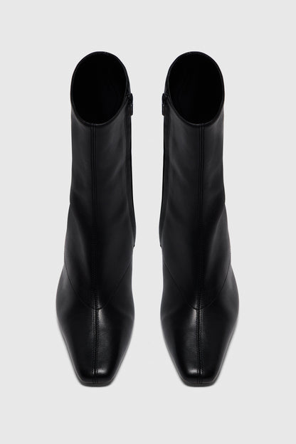 The Boots | Noir Leather by Realm—sleek, black leather high-heeled ankle boots crafted from smooth leather—make an essential addition to any capsule wardrobe, shown from above on a light grey background.
