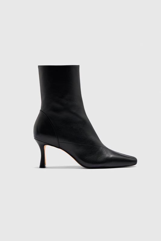 The Encore Ankle Boots by Realm are crafted from black leather, showcasing a pointed toe and a slim mid-height heel. Shown in profile against a plain light gray background, they are an essential addition to any capsule wardrobe.