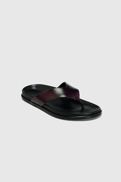 Realm’s Contour Flats in black leather feature wide, crisscrossed leather straps and a contoured footbed, shown on a light gray background.
