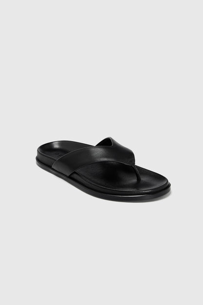 A single black leather flip-flop with a wide leather strap, toe post, and contoured footbed, shown on a plain light gray background.