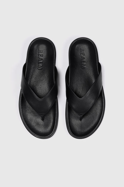 The Contour Flats in black leather by Realm feature wide crisscross straps and a contoured footbed—an effortless slip-on sandal.