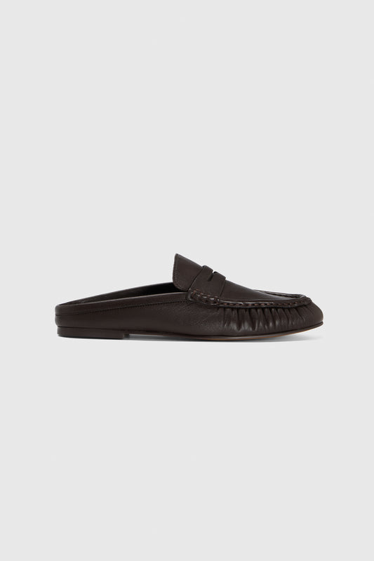 The loafers are shown in side profile, featuring black leather, a moccasin-style toe, and penny slot detail against a light gray background.
