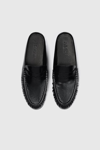 These everyday loafers in black leather feature a sleek slip-on design with rounded toes and textured soles, shown overhead on white.