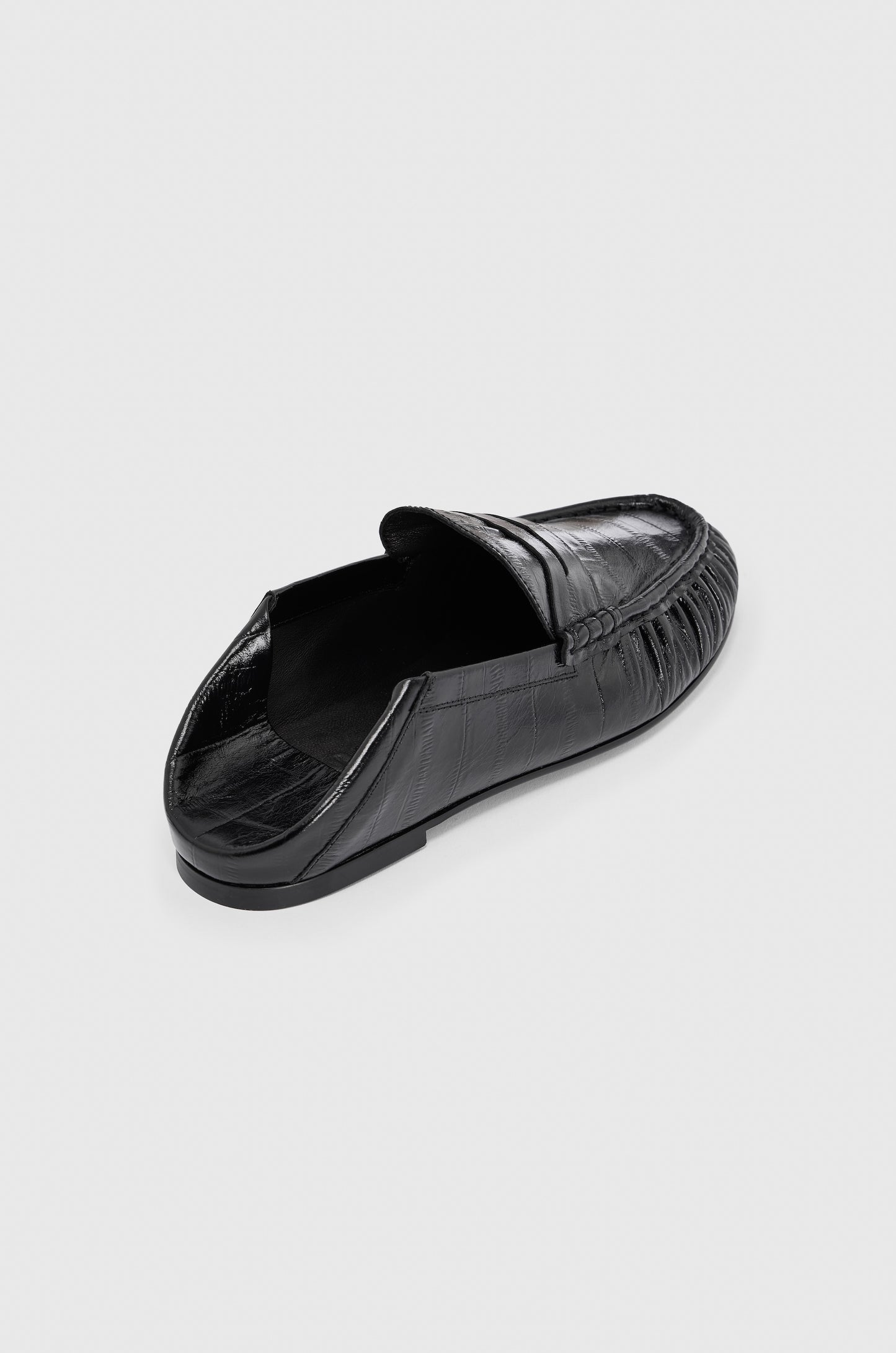 The Realm Form Loafers | Unagi Leather feature black embossed leather with a subtle crocodile pattern, displayed from an angled top view against a plain light gray background.