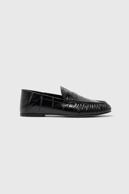 A single Realm Form Loafer | Unagi Leather is shown in profile against a light gray background, highlighting its black embossed leather with a shiny, textured finish, low heel, and slightly rounded toe.
