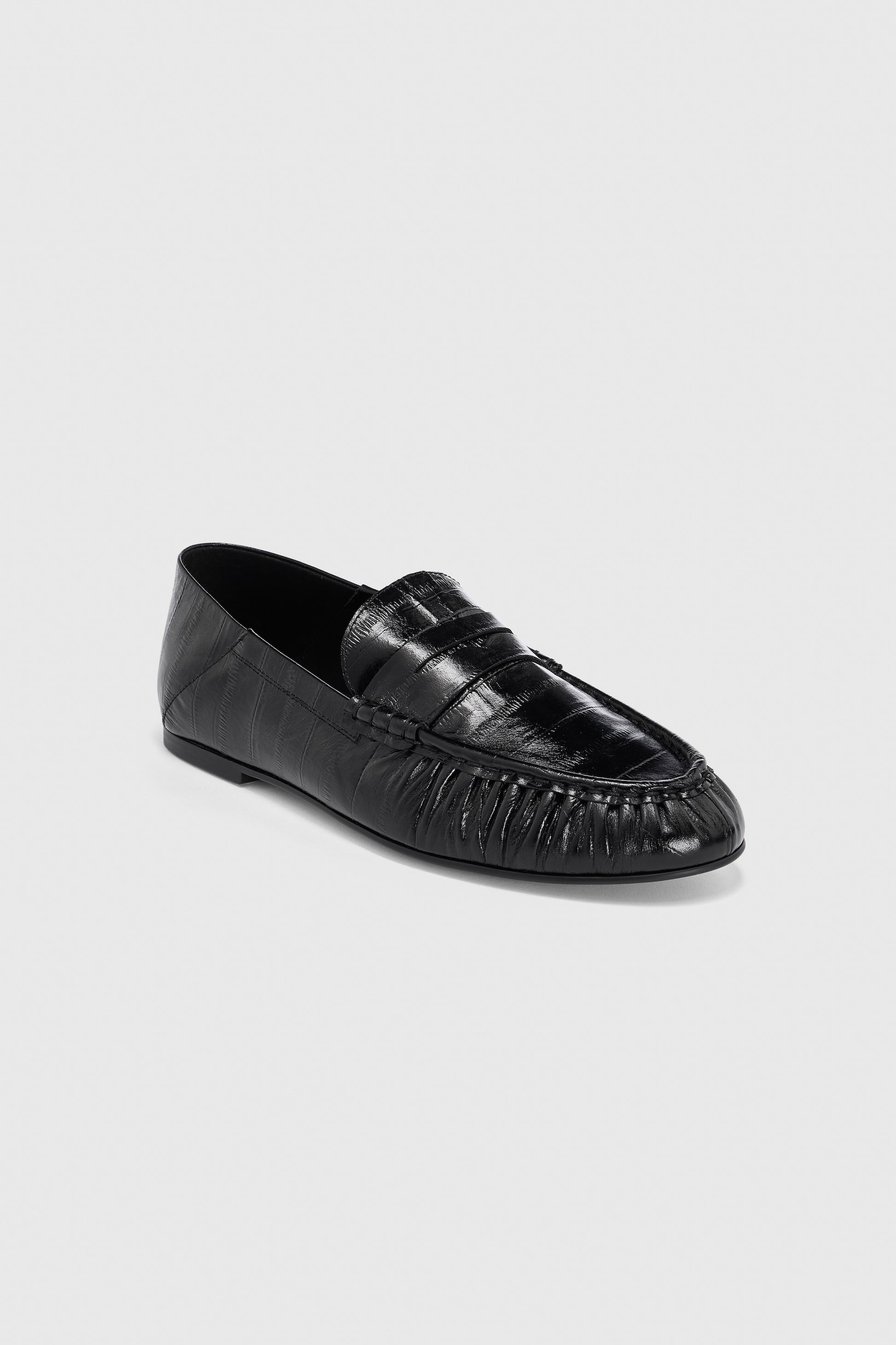 A pair of Realm Form Loafers | Gloss Black Leather in black embossed leather, featuring a moccasin-style toe, penny loafer strap, and subtle stitching details, displayed on a light gray background.