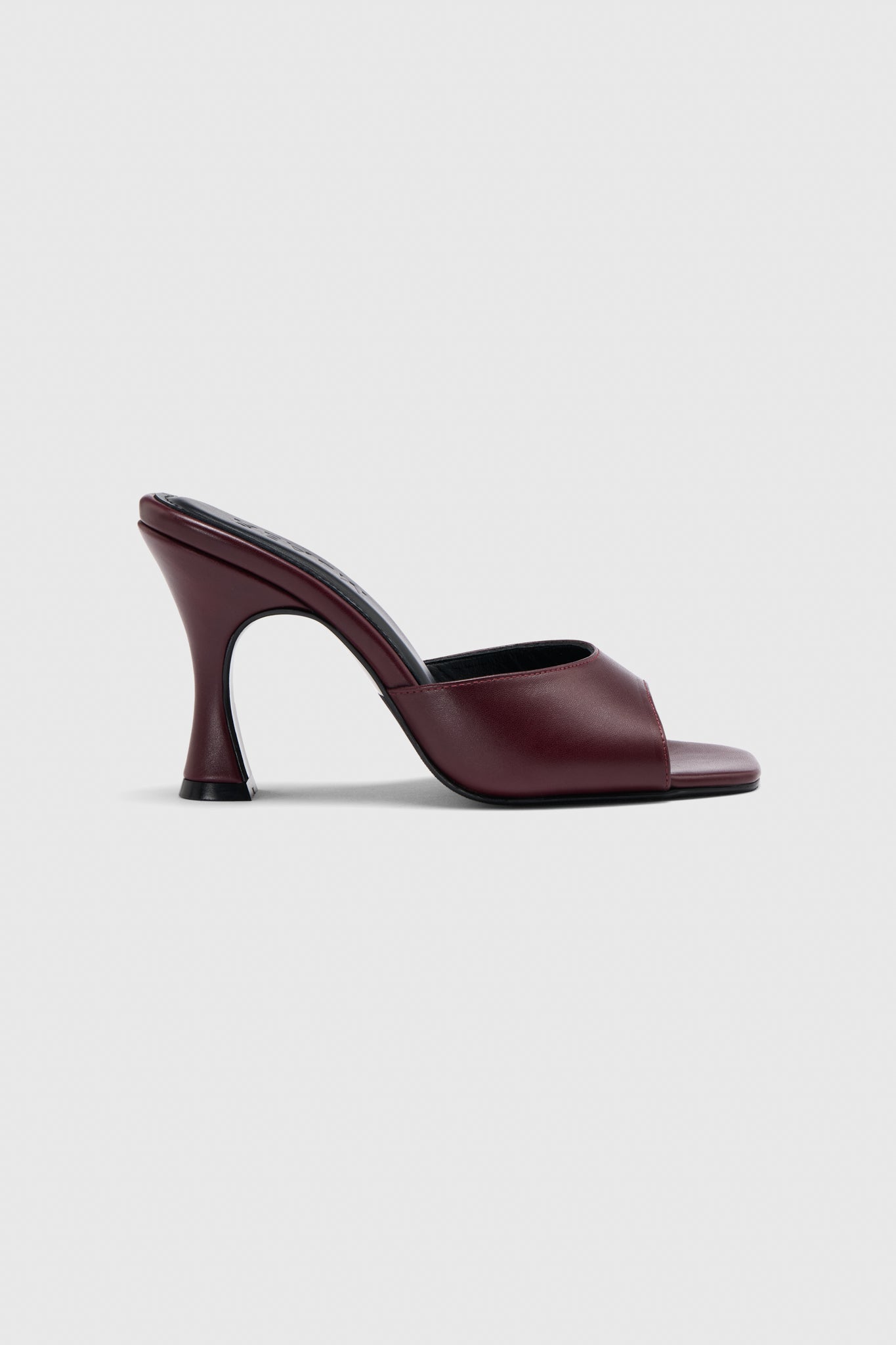 A single burgundy leather slip-on mule with open toe, wide strap, and curved flared heel, shown on a plain light gray background.